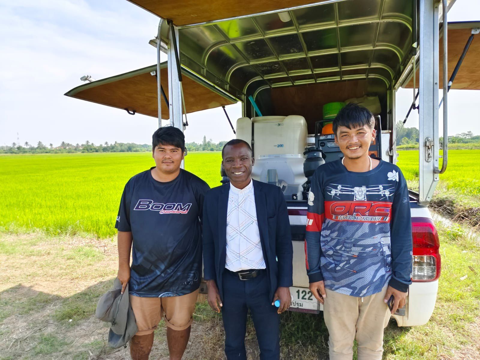 Drone operators with their service vehicle beside a rice field