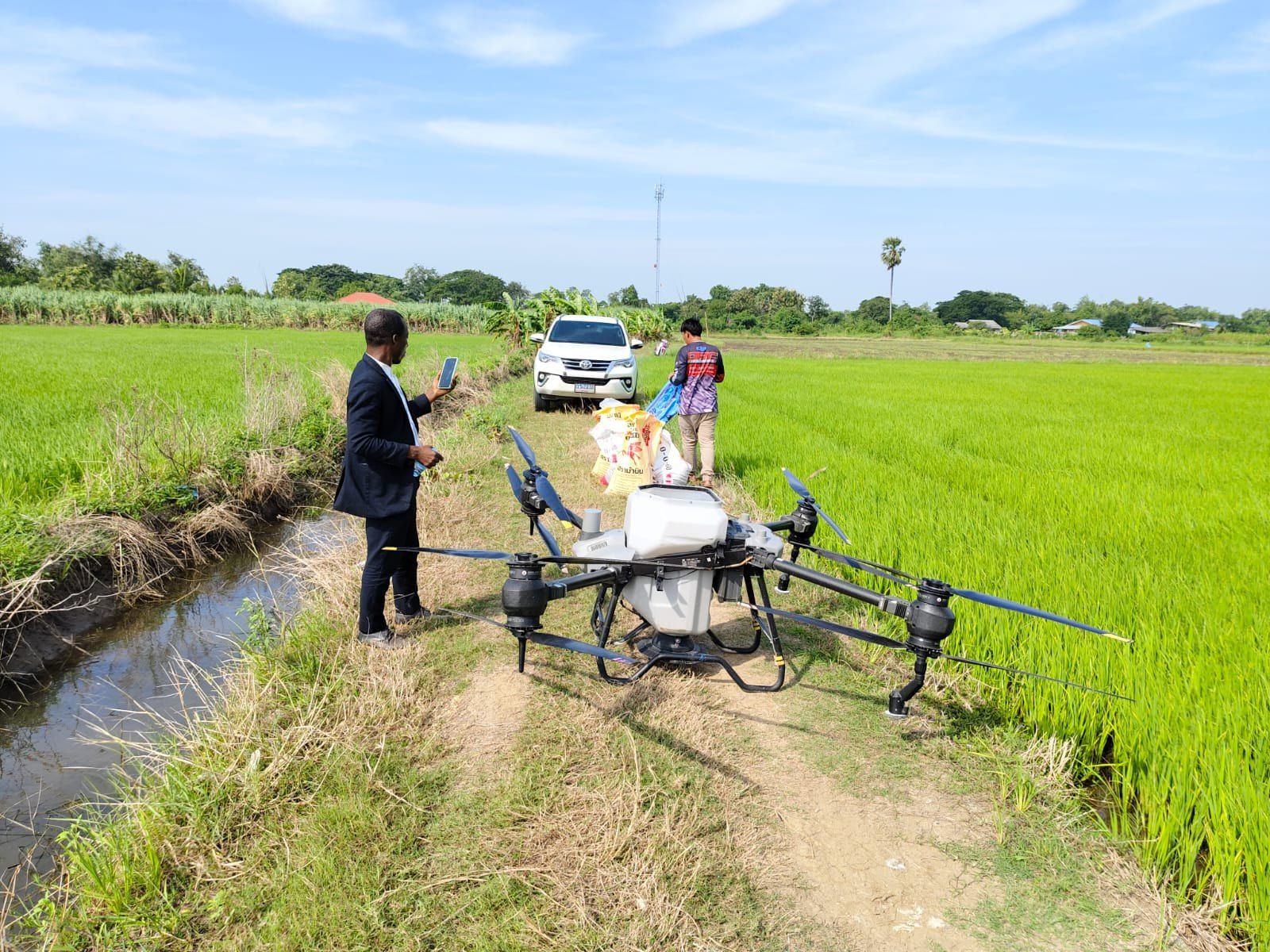 Agricultural spraying drone on a path between green rice fields