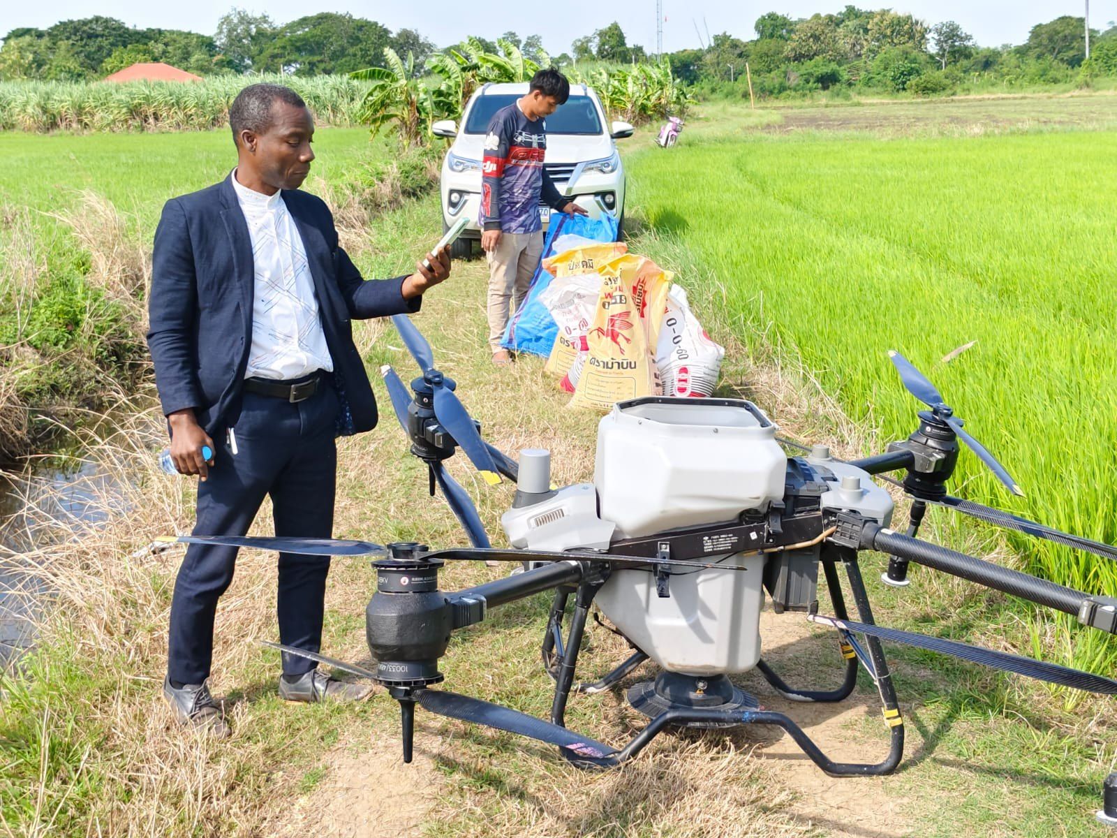Fertiliser bags being loaded for drone application at the edge of a rice field
